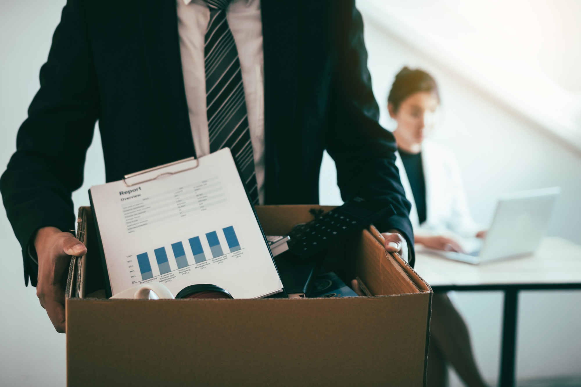 male employee standing holding office supplies in the paper box going to submit a resignation