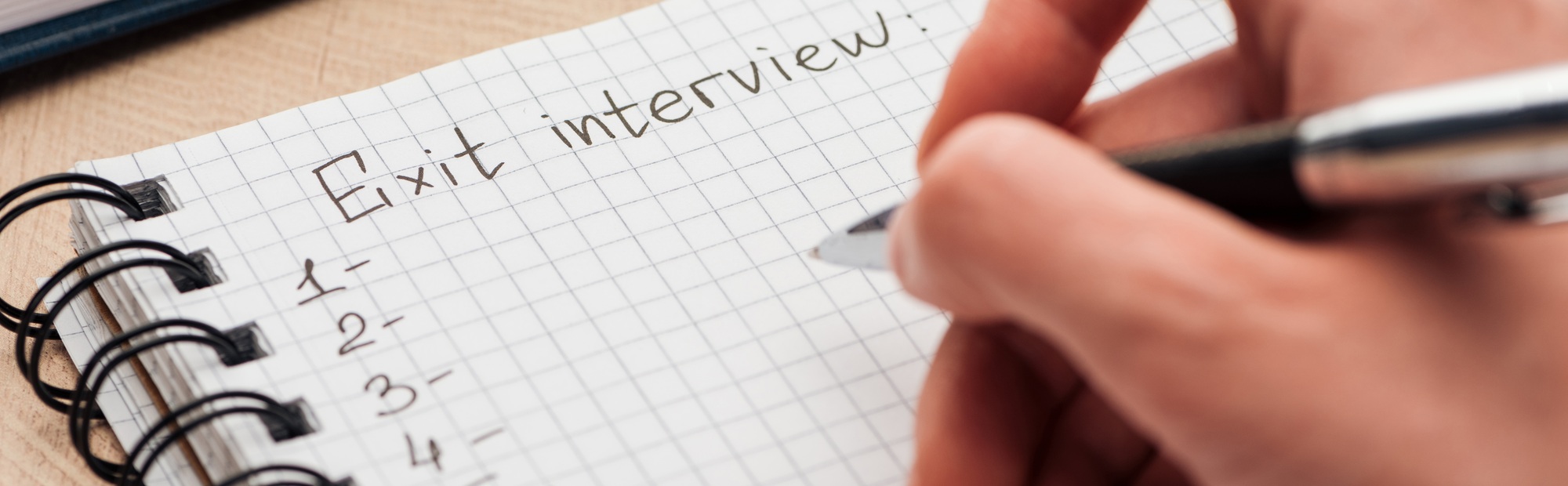 panoramic shot of recruiter writing in notebook with exit interview lettering