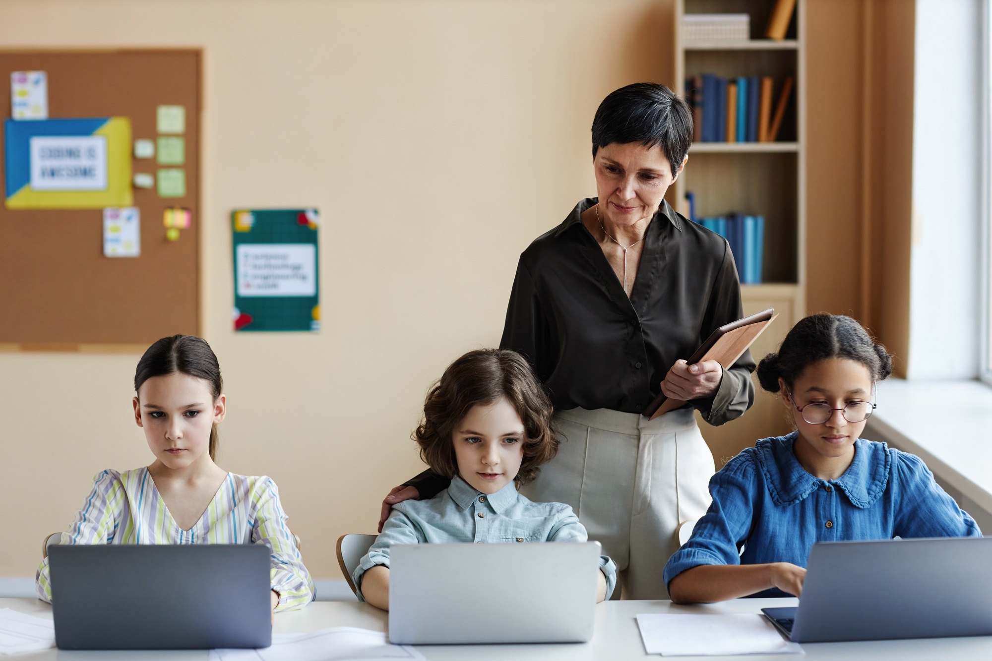 Teacher teaching students at information technology lesson